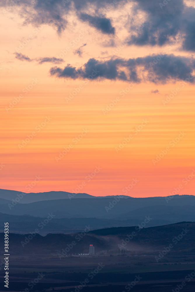 Wonderful landscape sunset clouds red orange yellow mountains fog industrial building dirty air pollution detail
