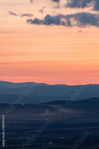 Wonderful landscape sunset clouds red orange yellow mountains fog industrial building dirty air pollution detail © Valentin