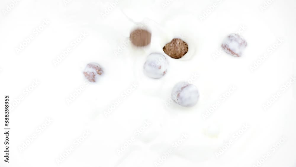 Chocolate corn cereal balls falling into organic milk in slow motion. Serving healthy breakfast cereal. Close-up. Natural food, morning clean eating concept, family nutrition, diet low-fat, vegetarian Chocolate corn cereal balls falling into organic milk in slow motion. Serving healthy breakfast cereal. Close-up. Natural food, morning clean eating concept, family nutrition, diet low-fat, vegetarian