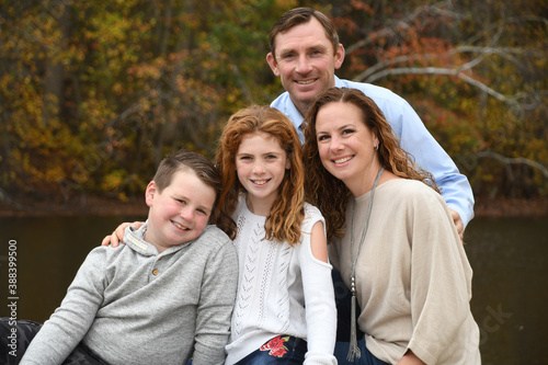 Autumn family portrait by the lake with mom, dad, son and daughter. 