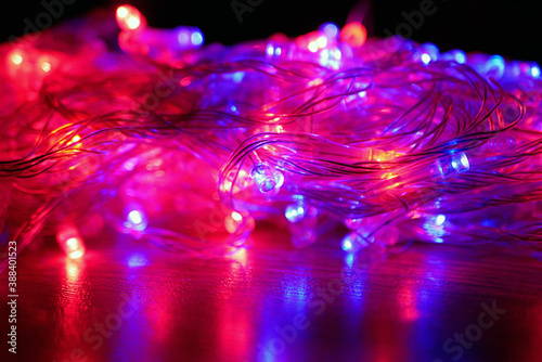 Illuminated christmas garland with red and blue lamps on black background. Focus on the middle ground.
