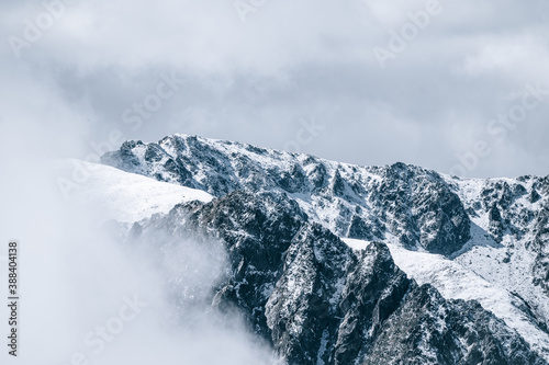 Snowy mountain peaks and glacier with clouds and fog. Winter snow landscape nature travel. Port d'Envalira, GrandValira, Pirineus, Pyrenees, Andorra.