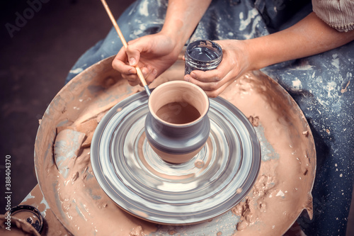 Artisan woman works with clay on a potter's wheel. Ceramics art concept. Close-up. photo