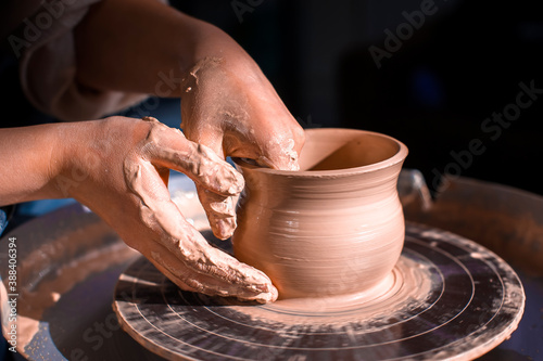 Craftsman's hands and potter's wheel. Close-up.