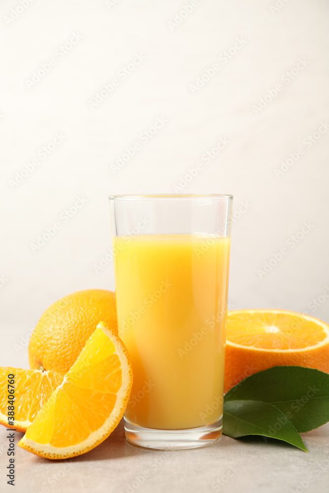 Tasty orange juice, fresh fruits and green leaves on light table Tasty orange juice, fresh fruits and green leaves on light table