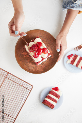Modelo femenina sosteniendo pastel red velvet crema de queso bizcocho de limon teñido de rojo topping de frutillas plano cenital vista aerea sobre plato