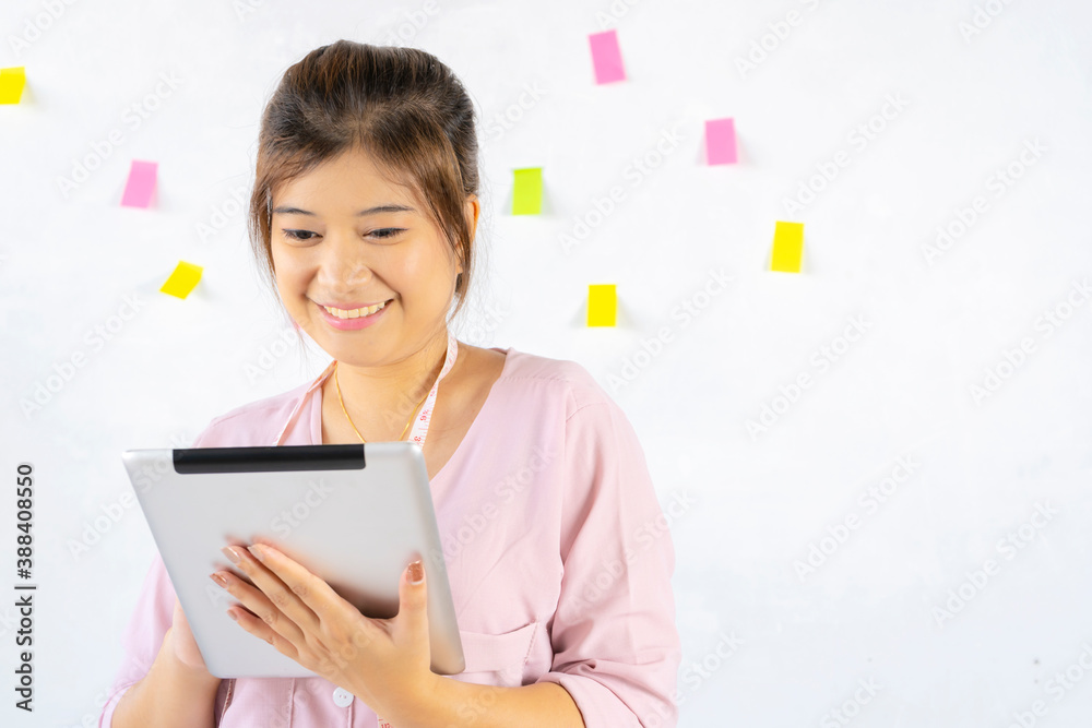Asian female designers holding gadget in hands using wi-fi internet in Living room with interior. Electronic wireless device concept Asian female designers holding gadget in hands using wi-fi internet in Living room with interior. Electronic wireless device concept