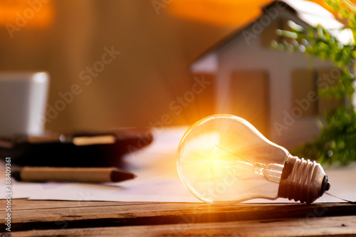 Light bulb with paper house on the table, a symbol for construction, Creative light bulb idea, power energy or business idea concept ecology, loan, mortgage, property or home.