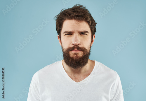 Handsome man with a beard on a blue background white t-shirt portrait