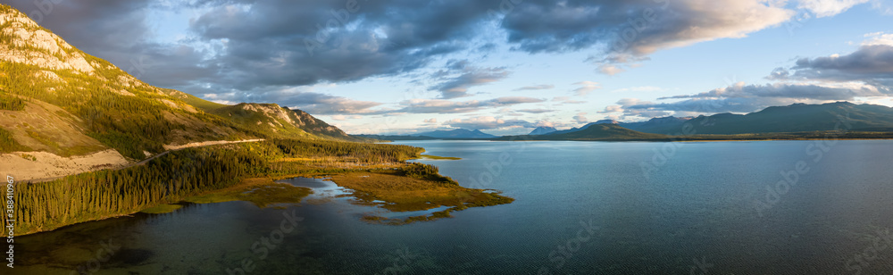 Gorgeous Panoramic View of Scenic Lake by Golden Moutain and Forest at Sunset in Canadian Nature. Aerial Drone Shot. Taken near Atlin, Yukon, Canada.