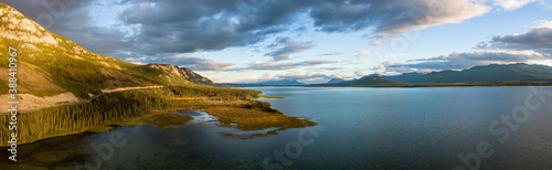 Gorgeous Panoramic View of Scenic Lake by Golden Moutain and Forest at Sunset in Canadian Nature. Aerial Drone Shot. Taken near Atlin, Yukon, Canada.