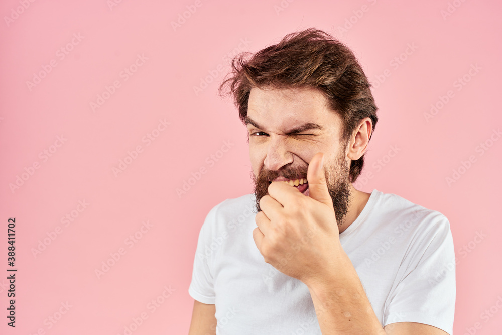 Bearded man in white t-shirt gesturing with hands facial expression close up pink background Bearded man in white t-shirt gesturing with hands facial expression close up pink background