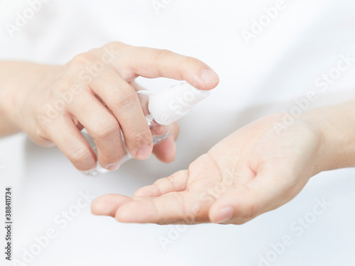 Close up view of women wearing white shirt using small portable alcohol gel, sanitizer hand gel bottles for killing bacteria, virus, germs on kid 's hand. © udom