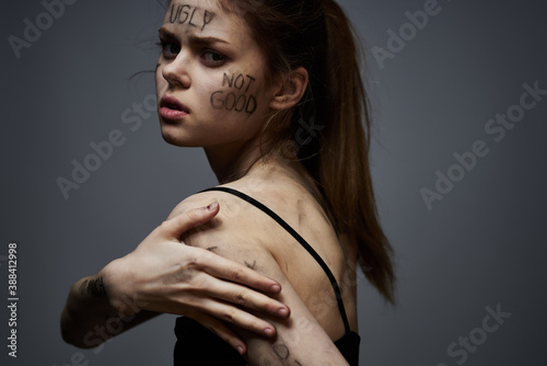 upset woman with offensive writing on her body on gray background touching herself with hands cropped view © SHOTPRIME STUDIO