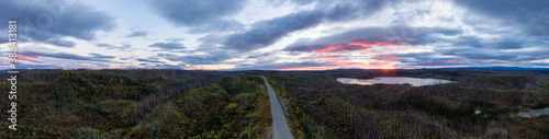 Panoramic View of Scenic Road surrounded by Forest and Lake at Sunrise in Canadian Nature. Aerial Drone Shot. Taken near Stewart-Cassiar Highway, North British Columbia, Canada.