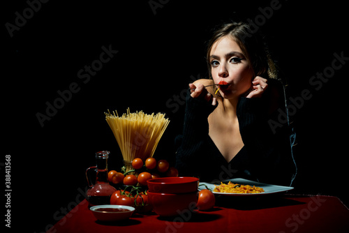 Hungry beautiful woman eat on noodles spaghetti on black background. photo