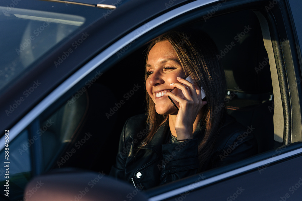Happy smiling woman speaking on the phone while driving a car on a sunny day. Received good news.