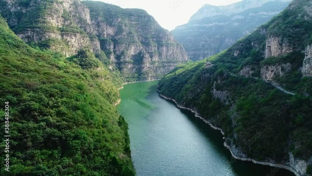 Aerial photography of green river in valley, steep cliff, tilt up