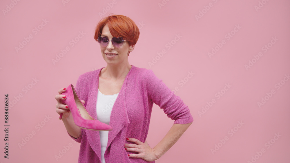 Mature woman with red short hair holding high heal shoes Isolated on purple background. High quality photo Mature woman with red short hair holding high heal shoes Isolated on purple background. High quality photo