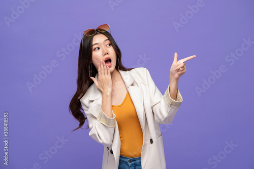 Fotografia Waist up portrait of shocked pretty Asian woman pointing hands to empty space as
