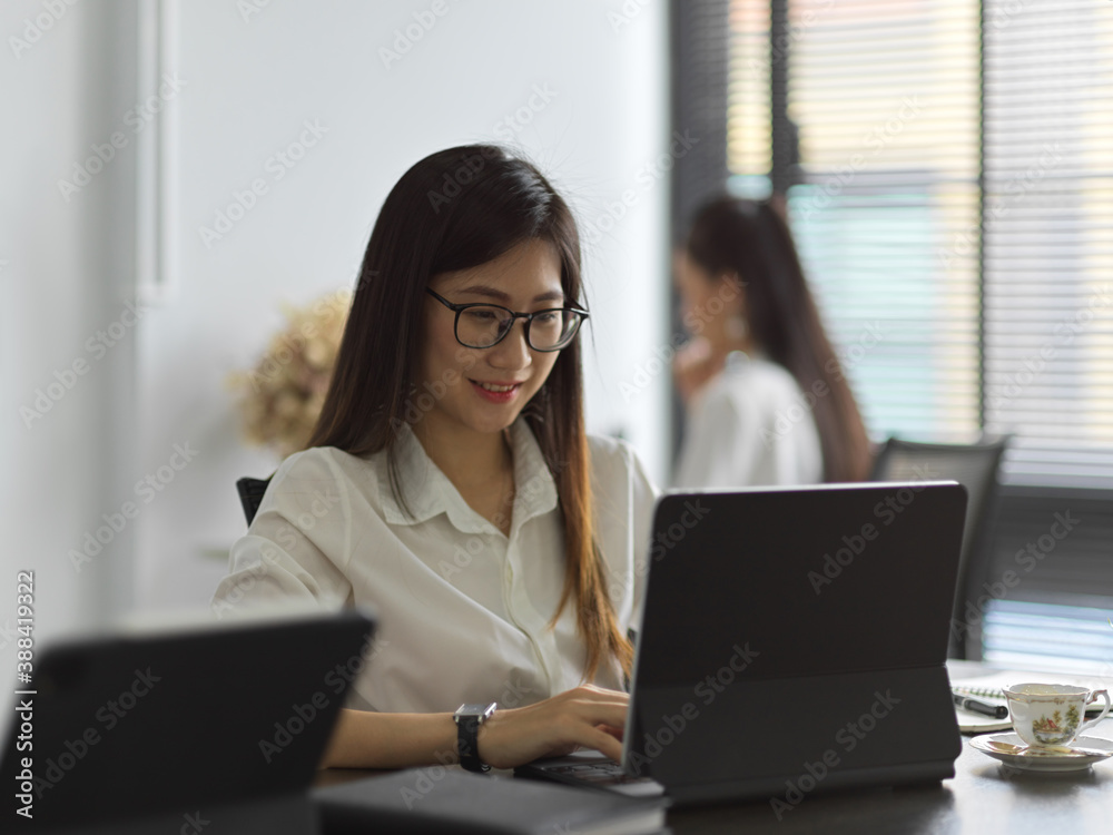 Female office worker working with laptop in office room