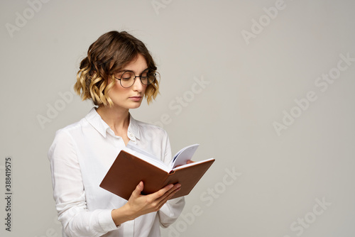 woman with notepad in hands business work beige background glasses hairstyle