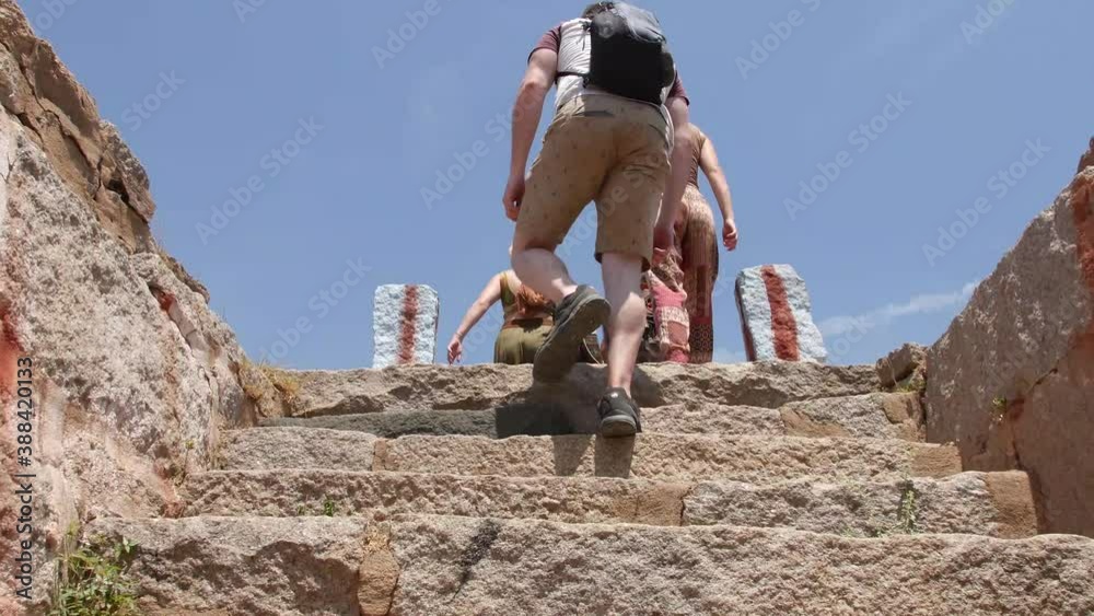 Hampi In India - Caucasian Tourists Climbing The Stone Stairs Of An Ancient Monument During A Summer Tour In Karnataka, India - Tracking Shot