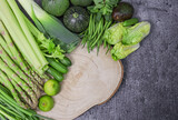 green vegetables on the stone
Green vegetables with a wooden board are arranged in a semicircle on the left with space for text on the right on a stone background, top view close-up.