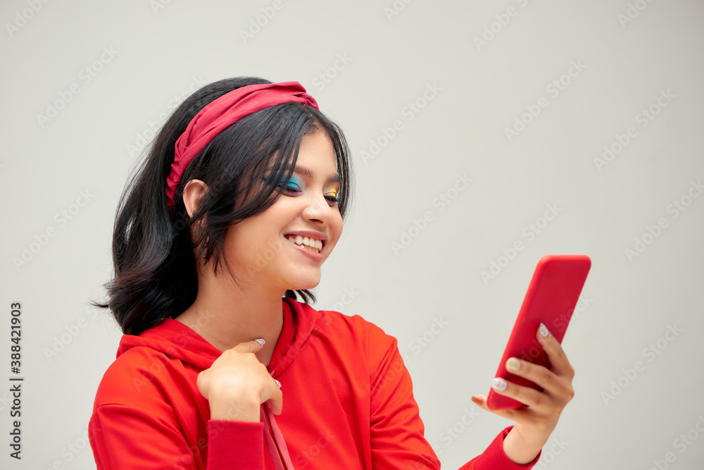 Smiling young woman girl posing isolated on gray background . Using mobile phone, typing sms message