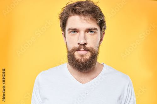 emotional bearded man in t-shirt cropped view yellow background studio