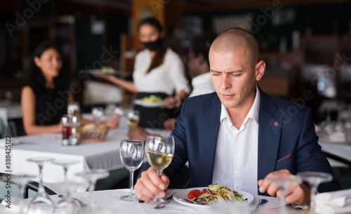 Portrait of young thoughtful businessman resting and having dinner in cozy restaurant