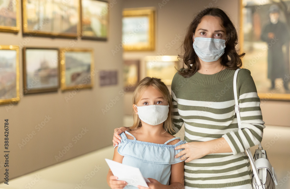 Mom and daughter in protective masks inspect the exhibits of the museum