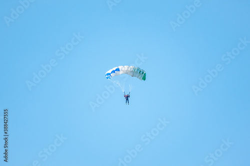 one parachutist floats slowly at low altitude on the background of clear sky