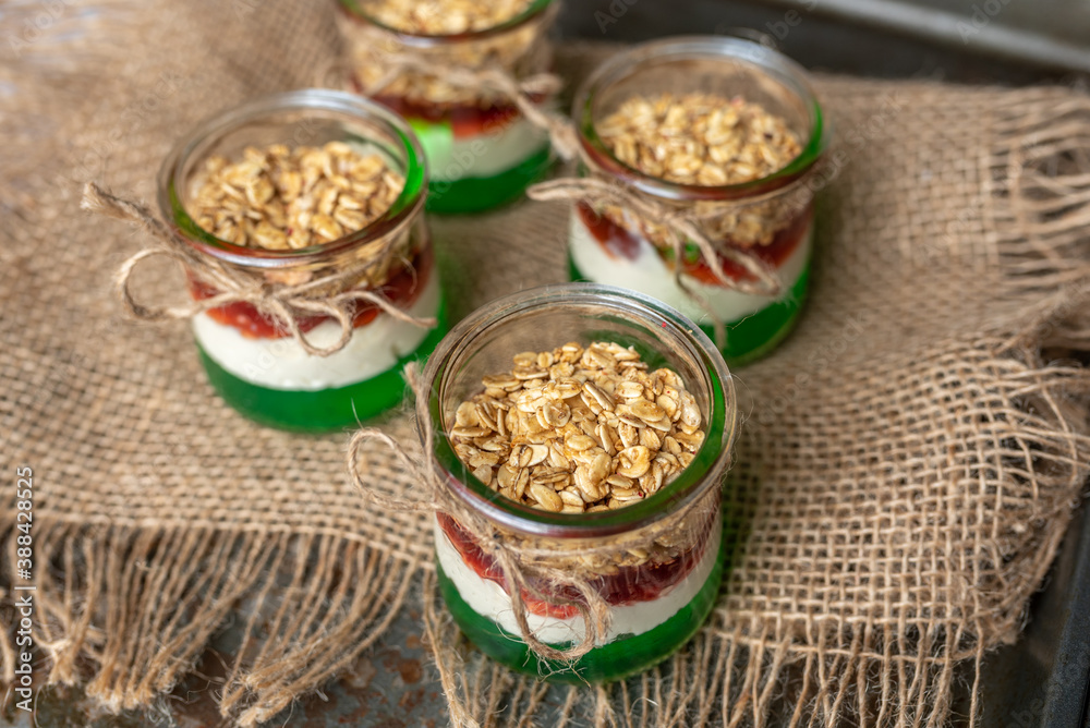 Yogurt with granola, decorated for Christmas with red and green jelly and jello. Christmas glass jar dessert Yogurt with granola, decorated for Christmas with red and green jelly and jello. Christmas glass jar dessert