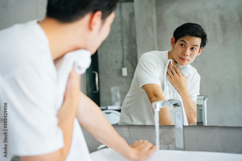 Young man washing and cleaning face with towel in bathroom. Young man washing and cleaning face with towel in bathroom.