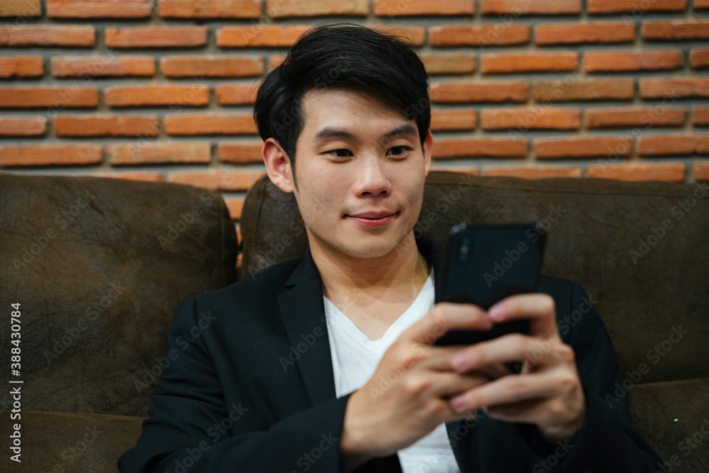 Asian young businessman using smartphone on sofa. Asian young businessman using smartphone on sofa.