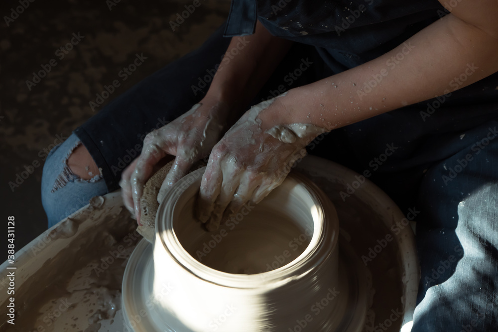 Hands of woman working with pottery wheel and making ceramic chamotte vase on it. dark and light Hands of woman working with pottery wheel and making ceramic chamotte vase on it. dark and light