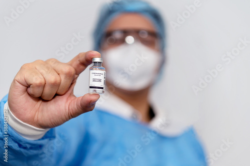 Coronavirus covid 19 disease expert hold samples of coronavirus covid 19 vaccine sample labelled coronavirus covid 19 with confidence and protective suit, mask and gloves
