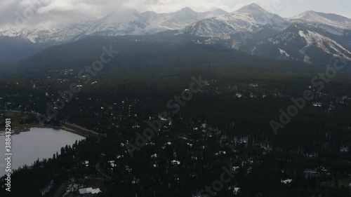 Aerial view over the town of Breckenridge, revealing mountains and clouds surrounding the area, on a sunny day, in Summit County, Colorado, USA - tilt up, drone shot photo