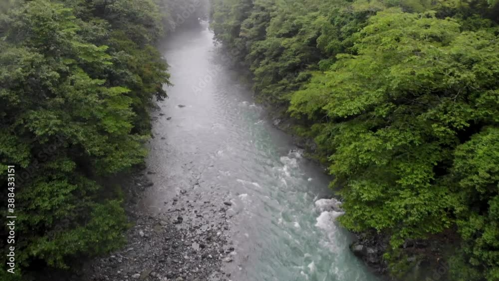 Forward moving drone shot over a clear, turquoise river to reveal upstream on a moody foggy rainy day. Shot of Tama River in Okutama. Forward moving drone shot over a clear, turquoise river to reveal upstream on a moody foggy rainy day. Shot of Tama River in Okutama.