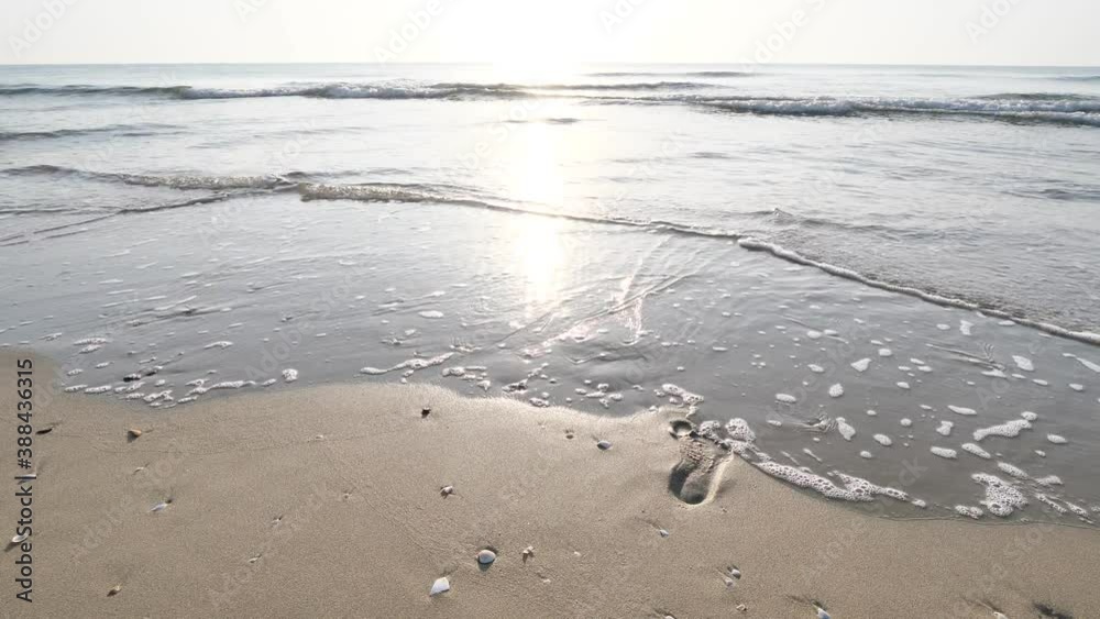 clear waves water lapping footprint on sand beach the white wave bubbles on sea shore in morning sun shine a beautiful seascape at sountern of Thailand clear waves water lapping footprint on sand beach the white wave bubbles on sea shore in morning sun shine a beautiful seascape at sountern of Thailand