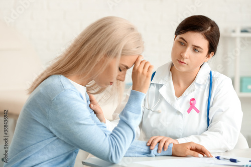 Sad young woman visiting doctor in clinic. Breast cancer awareness