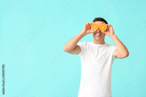 Funny man with ripe orange on color background