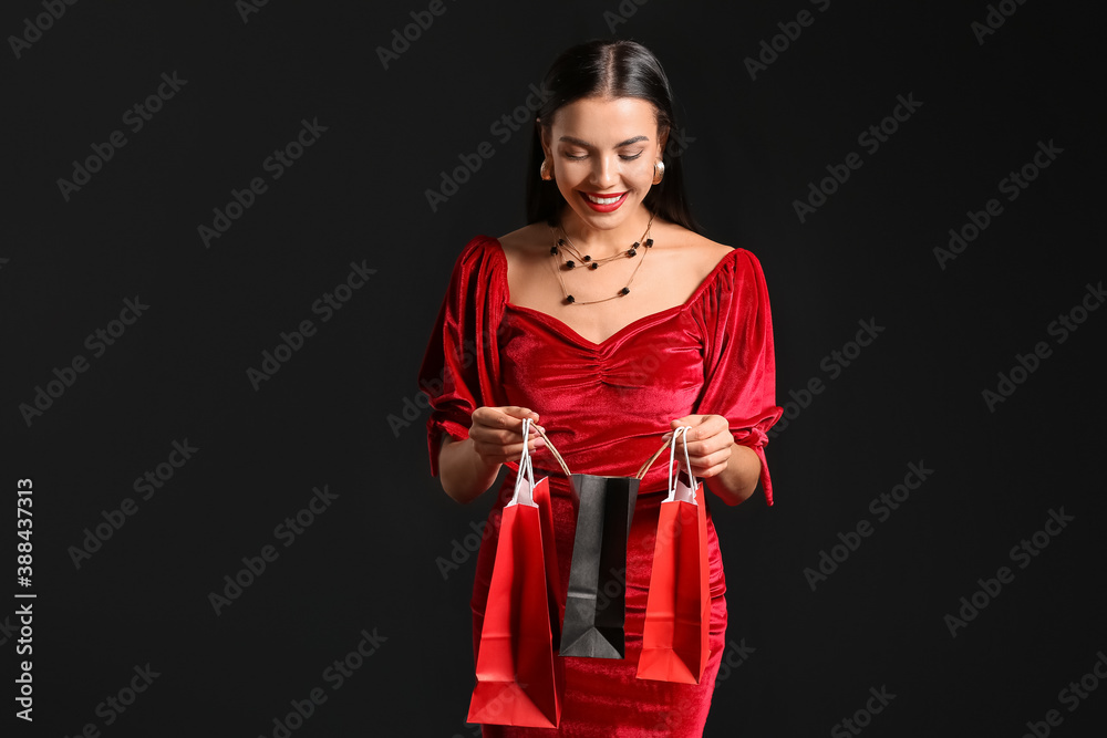 Beautiful young woman with shopping bags on dark background. Black Friday sale Beautiful young woman with shopping bags on dark background. Black Friday sale