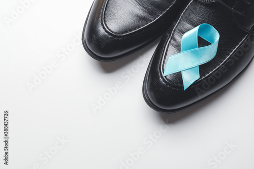 Male shoes with blue ribbon on white background. Prostate cancer awareness concept
