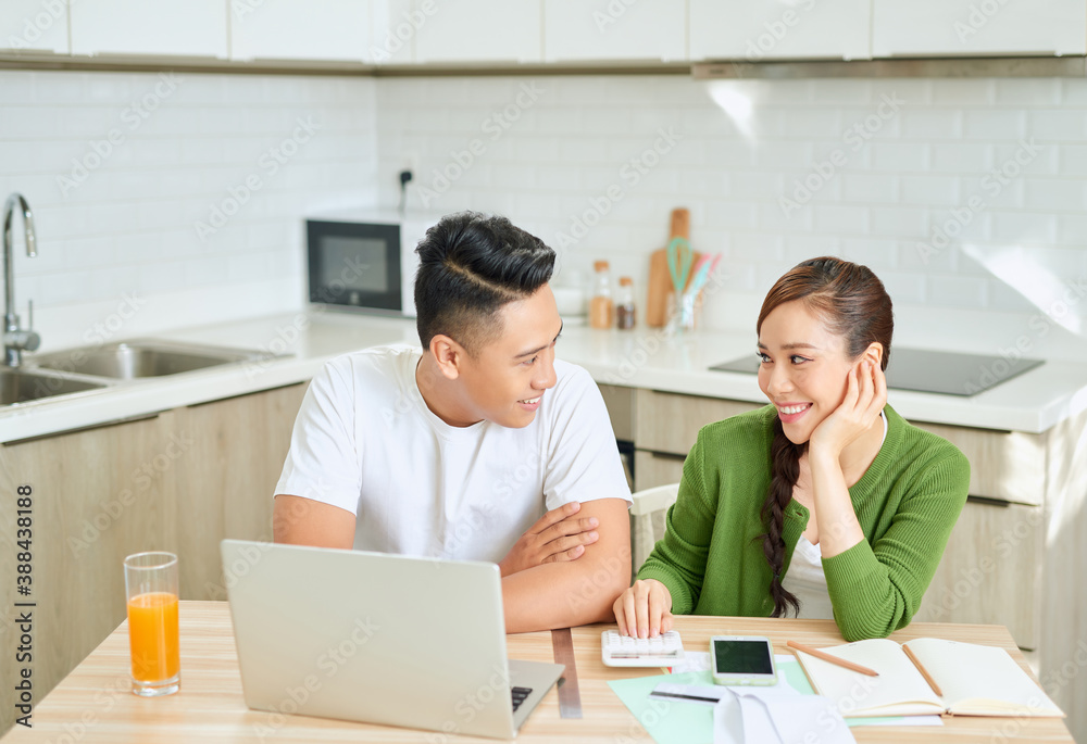 Photo of cheerful loving young couple using laptop and analyzing their finances with documents. Look at papers. Photo of cheerful loving young couple using laptop and analyzing their finances with documents. Look at papers.