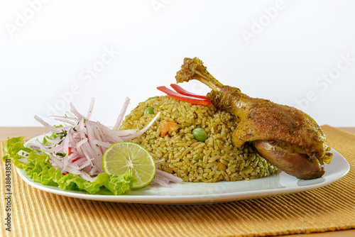Peruvian food, rice with duck, accompanied by onion, lemon and lettuce. White background.