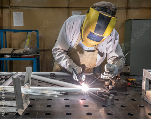 worker welds aluminum parts. Metalworking plant, the wizard in the mask