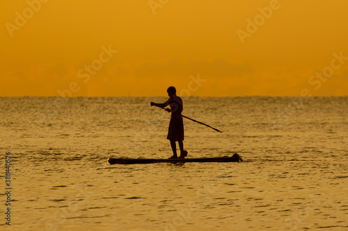 silhouette of a man at sunset in the sea on a board with a paddle