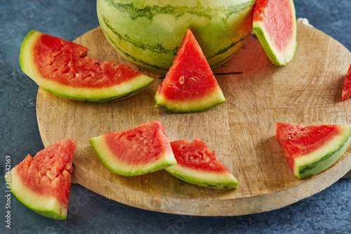 Mini Watermelon with sliced wedges on a round wooden stand on a blue background